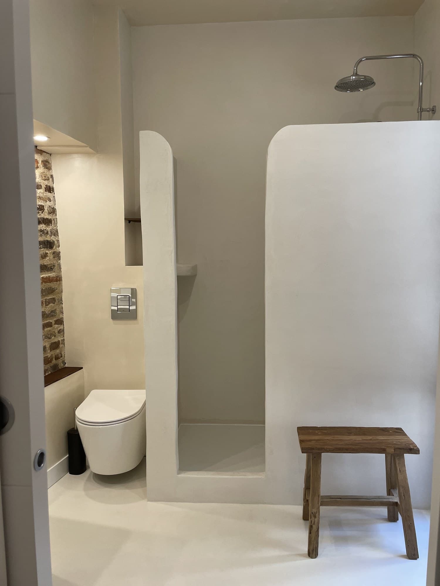 Salle d’eau entièrement en enduit : douche à l’italienne aux formes arrondies et WC suspendu